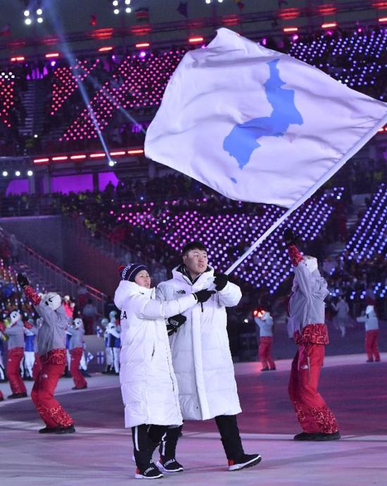 2月9日，朝韩两国代表团旗手黄忠琴（左）与元允宗在开幕式上举“朝鲜半岛旗”共同入场。当日，2018年平昌开幕式在平昌奥林匹克体育场举行。记者 吕小炜 图